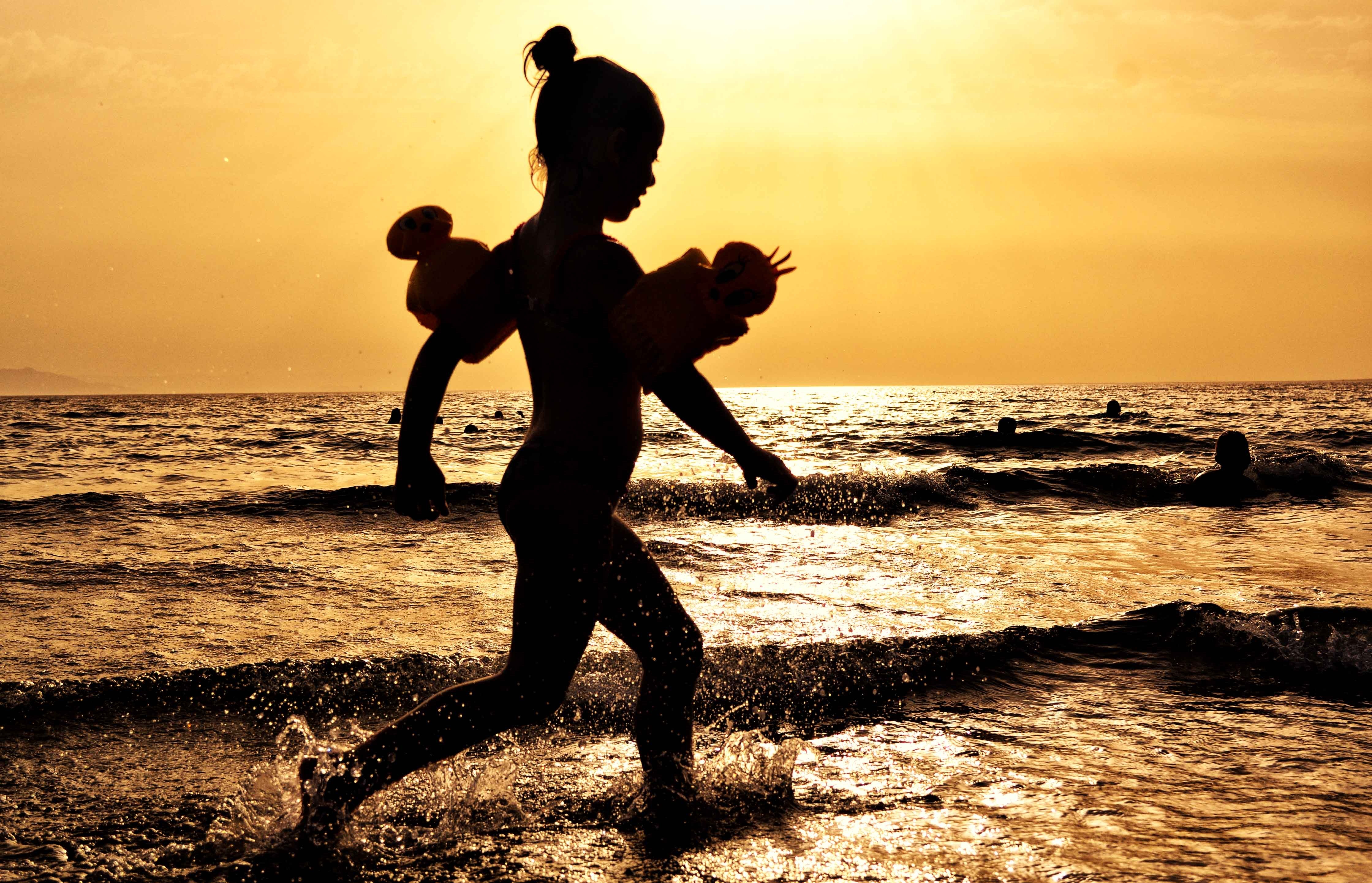 young girl in the surf at sunset